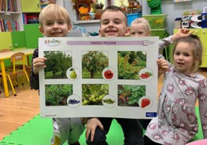 Przedszkolaki pokazują planszą z owocami